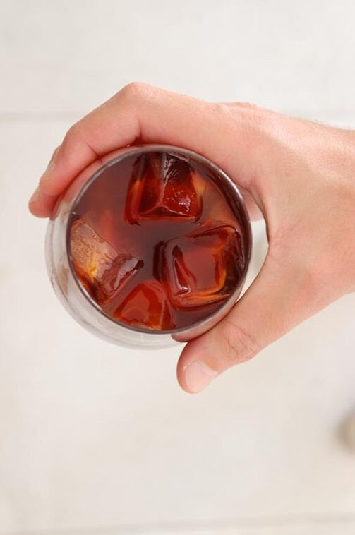 Someone holds a cup of cold brew iced coffe.