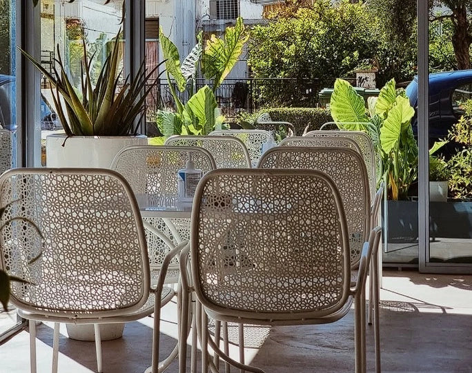 Outdoor patio with patterned chairs and potted plants on a sunny day.